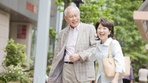 An elderly couple walking across the city arms crossed