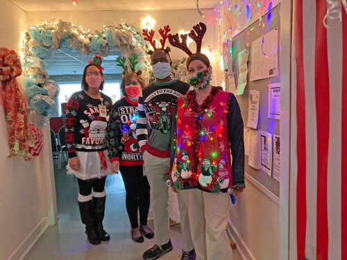 four people in christmas sweaters